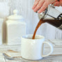 Pouring coffee from a French press coffee maker into a white mug. Morning ritual, drinking coffee, bright and airy lifestyle.