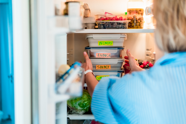 Healthy diet plan for weight loss, daily ready meal menu. Woman taking or putting lunch boxes cooked in advance, ready to be served into the fridge. 