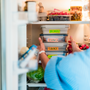 Healthy diet plan for weight loss, daily ready meal menu. Woman taking or putting lunch boxes cooked in advance, ready to be served into the fridge. 