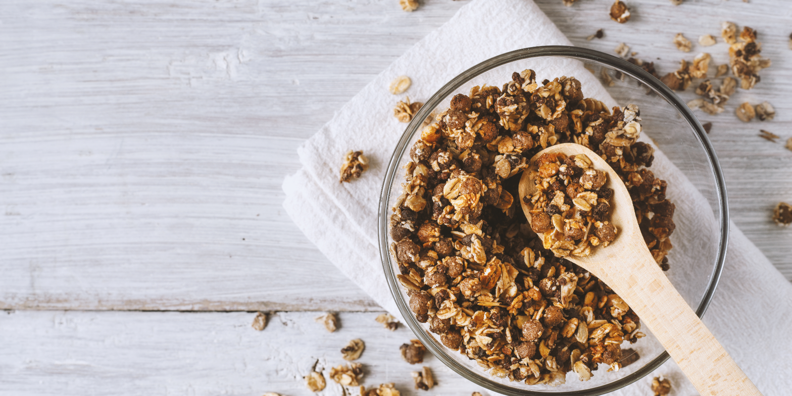 Homemade granola in a glass bowl on a white wooden table