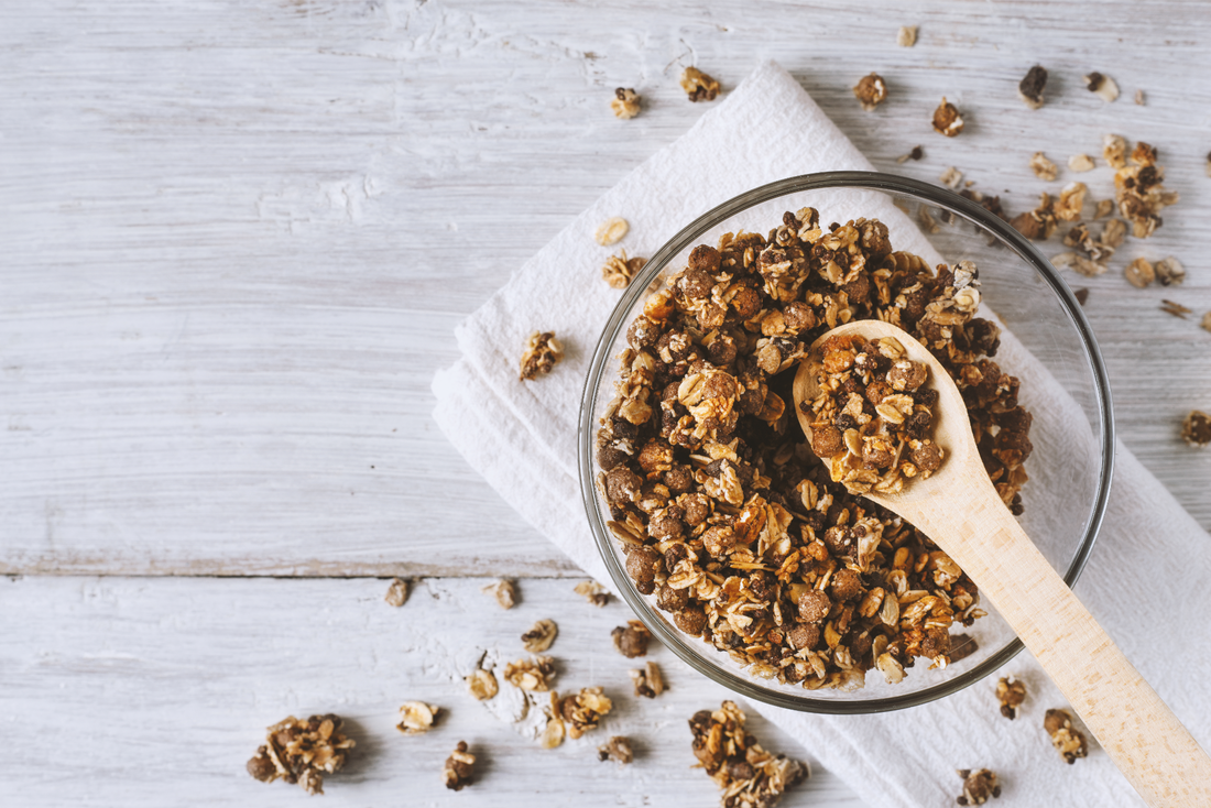 Homemade granola in a glass bowl on a white wooden table