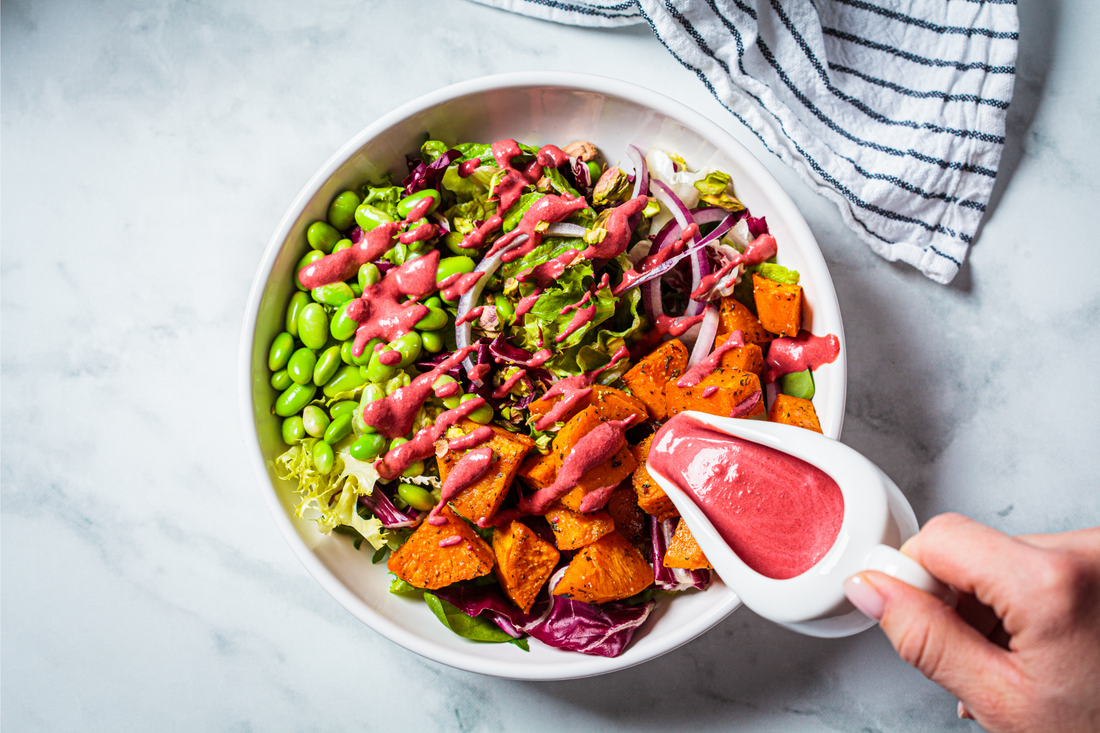Vegan salad bowl with baked sweet potatoes, edamame beans, nuts and pink beetroot dressing. Vegan food concept.