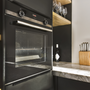 Contemporaty kitchen oven, clean countertops, wine glasses, kitchen utensils and tools.