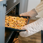 Hands taking out dried citrus with cloves from the oven. Natural cleaning methods