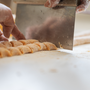 Closeup view of female hands cutting fresh homemade pasta dough to make vegan gnocchi.