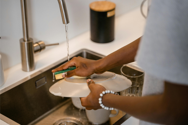 washing dishes, washing a plate with sponge in the kitchen sink 