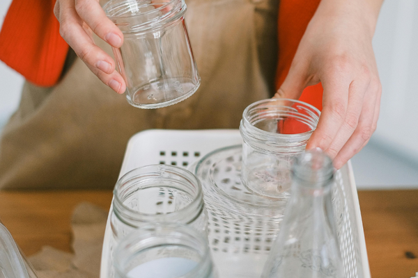 woman recycling glass containers in the kitchen. Reusing glass containers, eco-friendly, sustainable