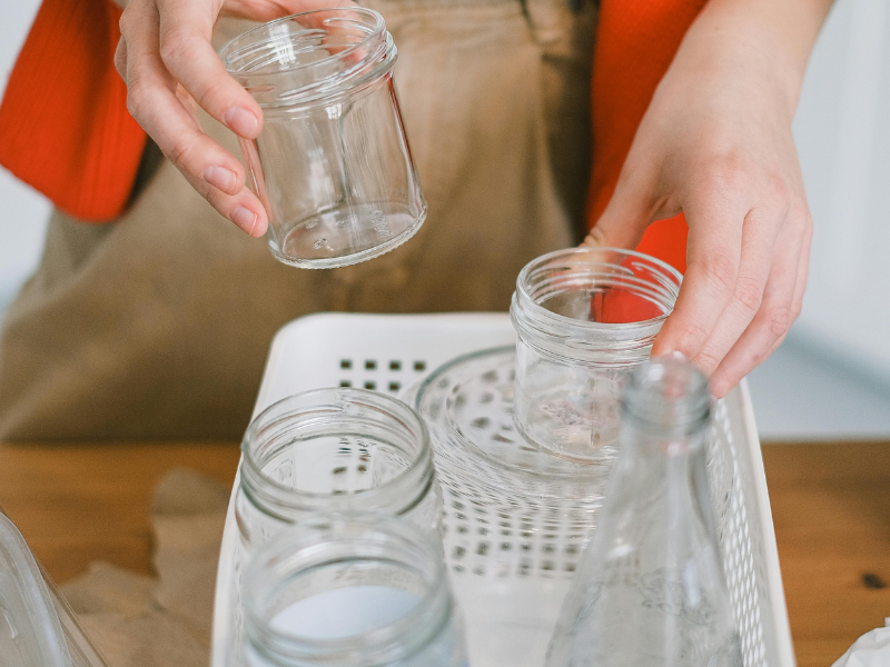 woman recycling glass containers in the kitchen. Reusing glass containers, eco-friendly, sustainable