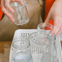 woman recycling glass containers in the kitchen. Reusing glass containers, eco-friendly, sustainable