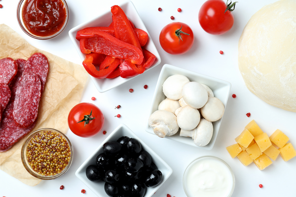 : Pizza ingredients on white background. Tomatoes, black olives, tomato sauce, cheese, pizza dough, bell pepper, mushrooms.