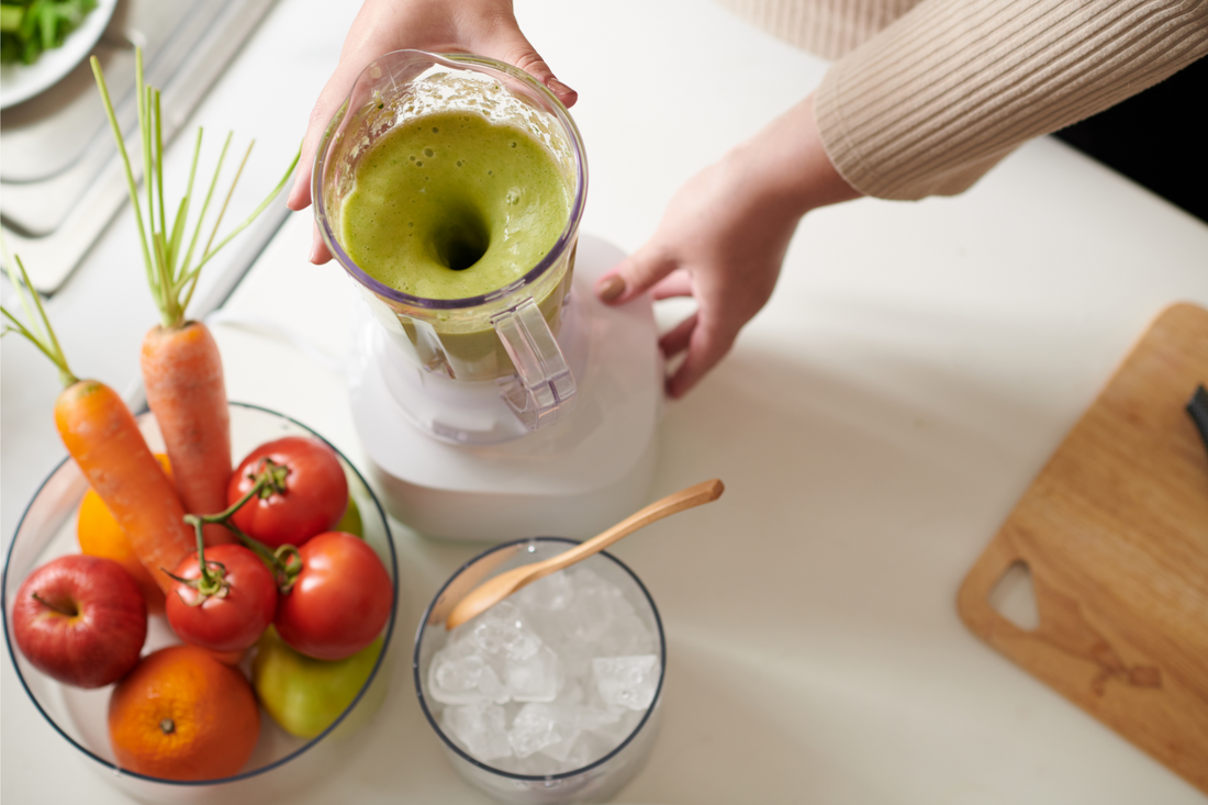 Blender with green smoothie, bowl of ice and bowl of fresh vegtable on kitchen table of woman