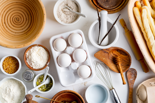 Natural organic ingredients for homemade production of fresh healthy bread of other pastry - eggs, wheat and rye flour, cane sugar and pumpkins seeds on a light gray background. 