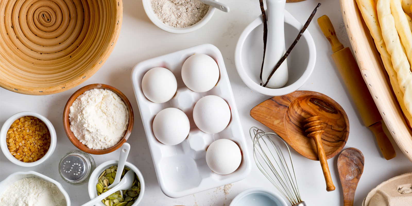 Natural organic ingredients for homemade production of fresh healthy bread of other pastry - eggs, wheat and rye flour, cane sugar and pumpkins seeds on a light gray background. 