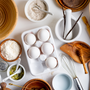 Natural organic ingredients for homemade production of fresh healthy bread of other pastry - eggs, wheat and rye flour, cane sugar and pumpkins seeds on a light gray background. 