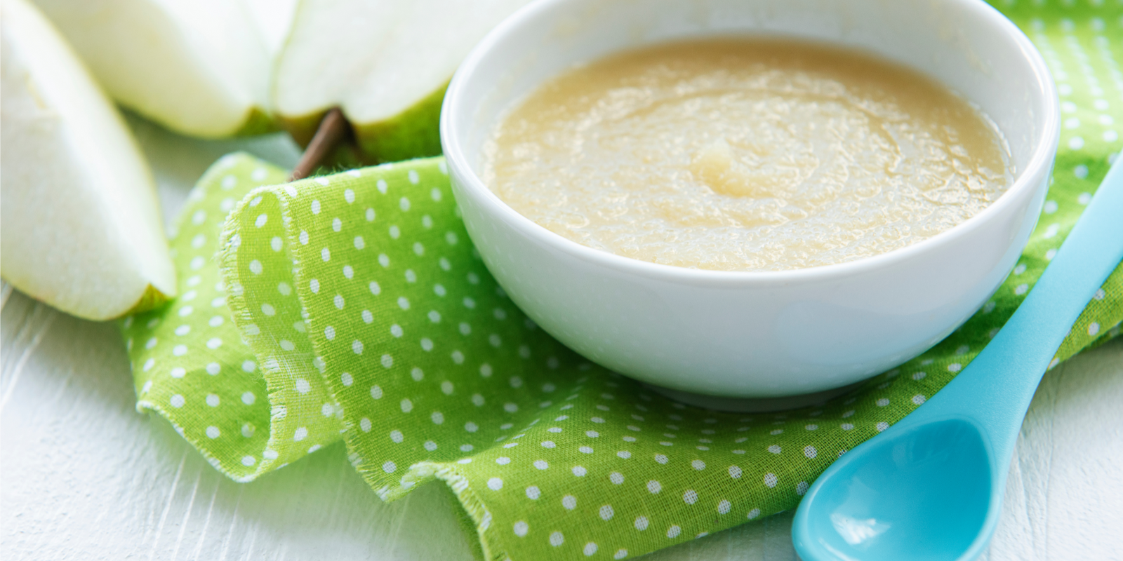 Bowl with homemade baby food and pears on table