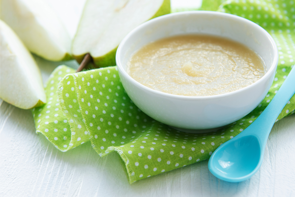 Bowl with homemade baby food and pears on table