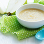 Bowl with homemade baby food and pears on table