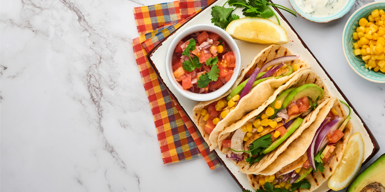 Mexican tacos with grilled chicken, avocado, corn kernels, tomato, onion, cilantro and salsa at white stone table. Traditional Mexican and Latin american street food. Top view.