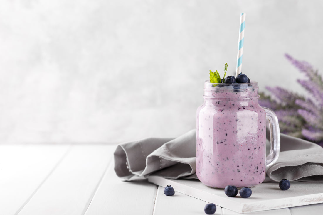 Blueberry smoothie in a glass jar garnished with berries, horizontal copy space.