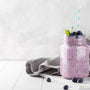 Blueberry smoothie in a glass jar garnished with berries, horizontal copy space.