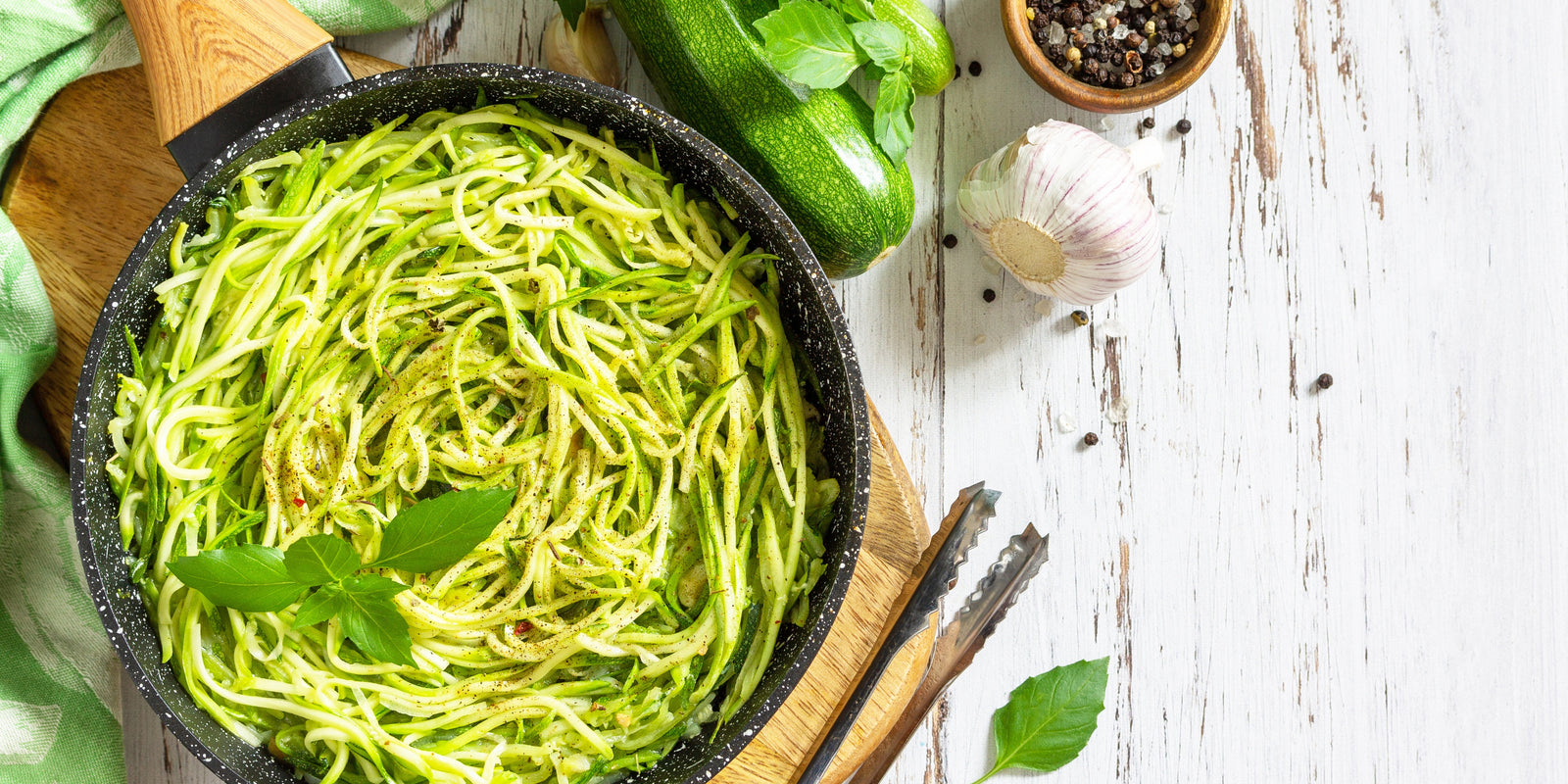 Healthy vegan food, low carb dish. Cooked zucchini noodles with basil and garlic on a rustic wooden table