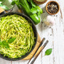 Healthy vegan food, low carb dish. Cooked zucchini noodles with basil and garlic on a rustic wooden table