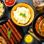 Holiday german dishes - sauerkraut, sausage, pretzel, mashed potato and beer. Top view on black table.