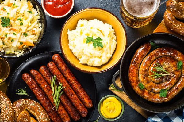 Holiday german dishes - sauerkraut, sausage, pretzel, mashed potato and beer. Top view on black table.