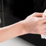 panoramic shot of woman cleaning microwave with rag in kitchen