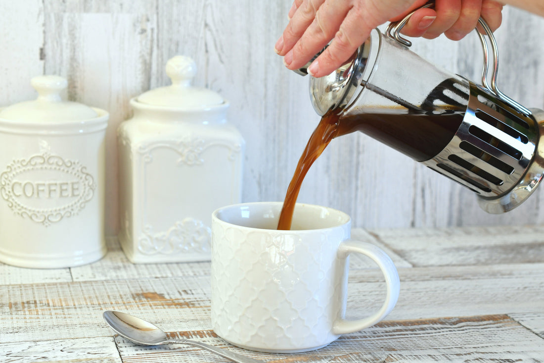 Pouring coffee from a French press coffee maker into a white mug. Morning ritual, drinking coffee, bright and airy lifestyle. 
