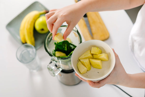 Girl making healthy drink. Ingredients for green healthy smoothie - bananas, apples, spinach and water