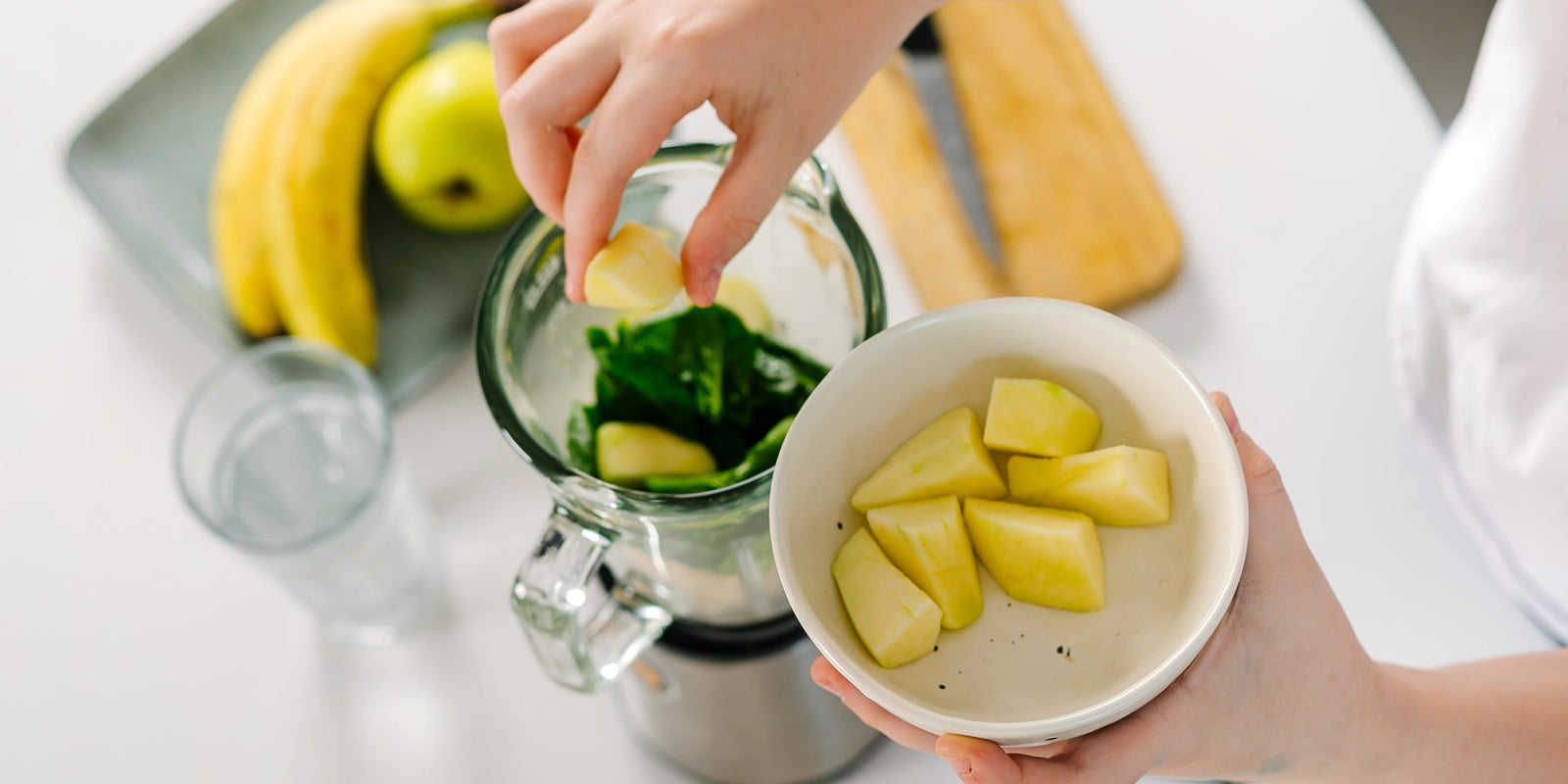 Girl making healthy drink. Ingredients for green healthy smoothie - bananas, apples, spinach and water