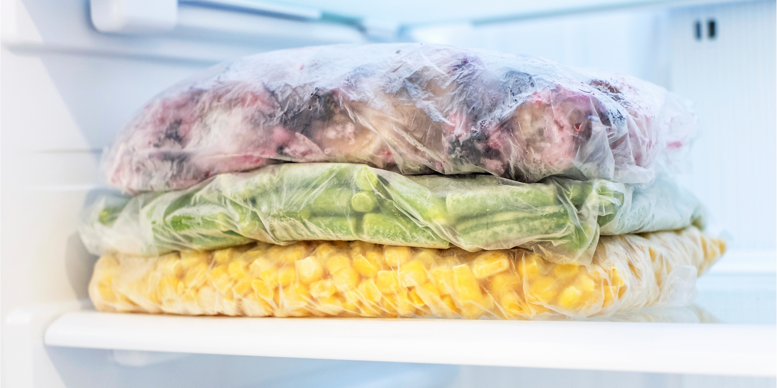 Shelf with frozen food in the refrigerator close up front view