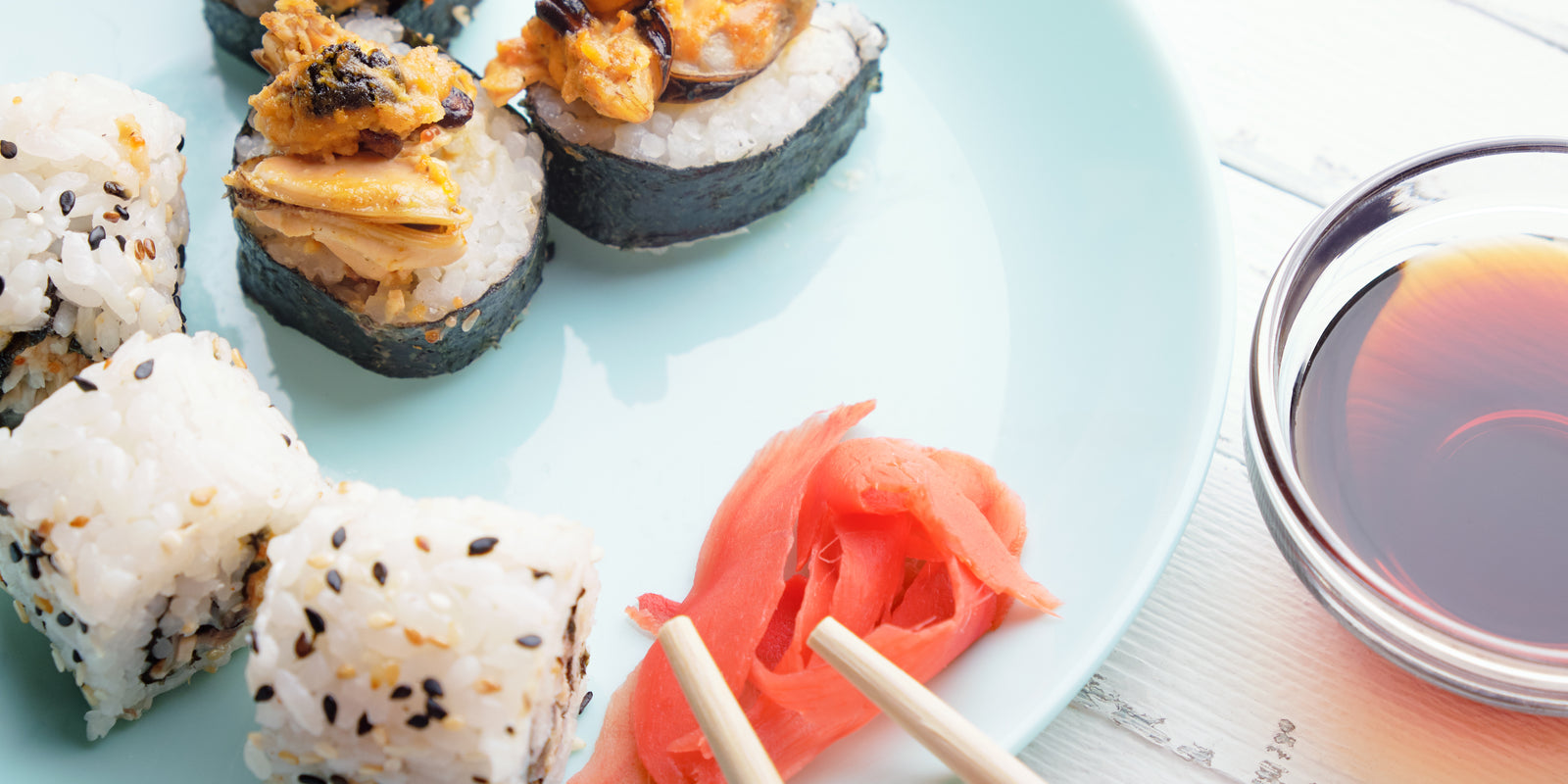 Sushi rolls in blue plate, chopsticks and soy sauce